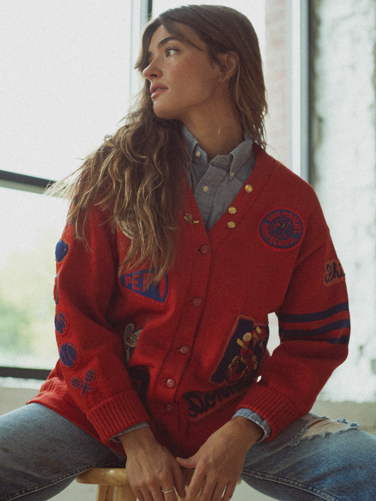 Red chenille letter cardigan from San Manuel High School, Arizona, covered in felt and chenille patches, worn over a chambray shirt