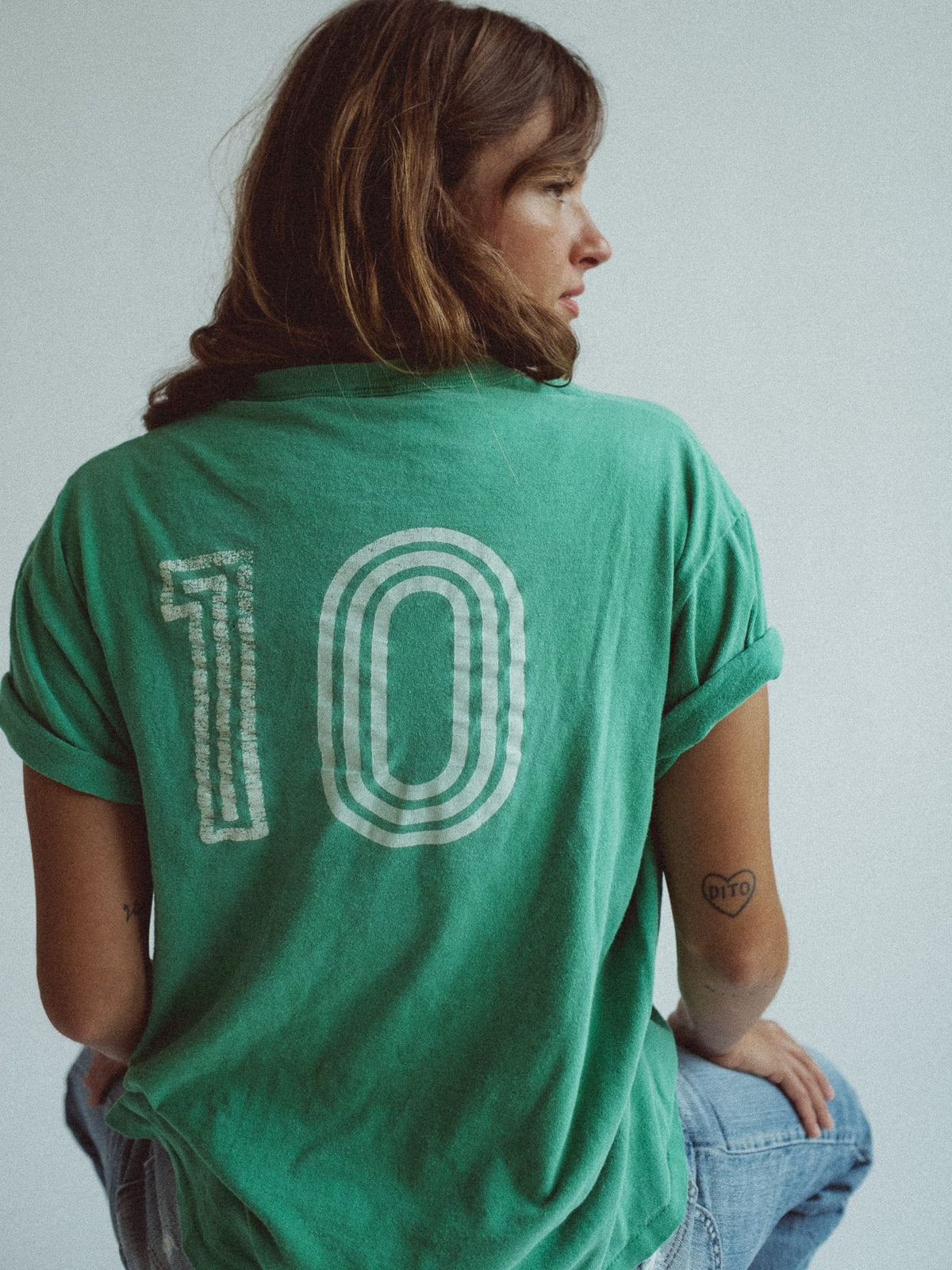 Kelly green tee seen from the back, printed with a large nested-outline numeral 10 in cracked white